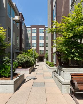 Seattle apartment for rent - a sidewalk with benches and trees in front of a building