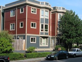 Seattle apartment for rent - A black car is parked in front of a red and grey building.