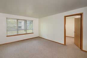 Seattle apartment for rent - A room with a carpeted floor, a window with blinds, and a door.