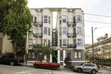 San Francisco apartment for rent - A red truck is parked in front of a white building with black railings.