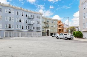 San Francisco apartment for rent - A parking lot with a white truck and a grey building with a fire escape.