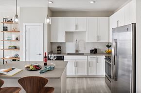 Tampa apartment for rent - Bainbridge at Westshore Marina Kitchen with white shaker cabinets, light gray flooring, light gray quartz countertops, white tile backsplash, and stainless steal appliances