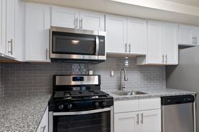 Wayne apartment for rent - a kitchen with white cabinets and a stove and a microwave
