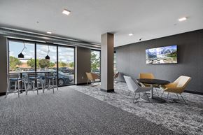 Bloomington apartment for rent - a lounge area with tables and chairs and a television on the wall