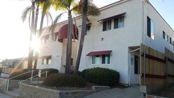 San Diego apartment for rent - A white building with a red awning and a wooden fence in front.