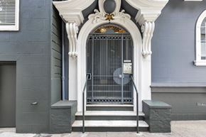 San Francisco apartment for rent - A grey building with a white door and a fan on the wall.
