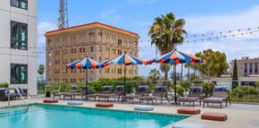 San Pedro apartment for rent - a swimming pool with chairs and umbrellas next to a building
