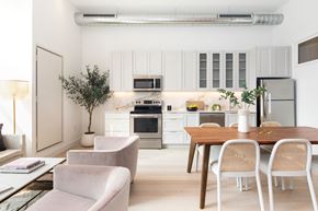 Philadelphia apartment for rent - a kitchen and dining room with white cabinets and appliances and a wooden table