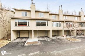 Anchorage apartment for rent - A large, beige building with a flat roof and a parking lot in front.