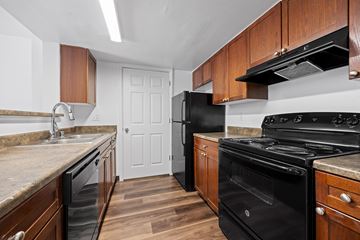 Denver apartment for rent - A kitchen with black appliances and wooden cabinets.
