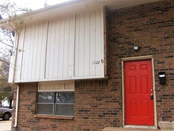 Wichita apartment for rent - A red door is on the right side of a brick house.