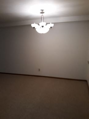 Sussex apartment for rent - A chandelier hangs from the ceiling in a room with a carpeted floor.