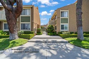 Buena Park apartment for rent - A row of apartment buildings with trees and a walkway in front.