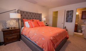 Oklahoma City apartment for rent - A bedroom with a bed covered in orange bedding.