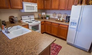 Oklahoma City apartment for rent - A kitchen with a white fridge, white microwave, white stove and white sink.