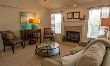 Edmond apartment for rent - A living room with a fireplace, a chair, a sofa, and a painting on the wall.