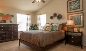 Edmond apartment for rent - A bedroom with a bed, nightstand, and a ceiling fan.
