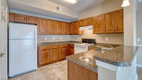 Orange apartment for rent - an empty kitchen with wooden cabinets and a white refrigerator