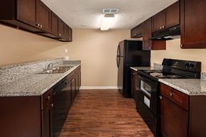 Port Arthur apartment for rent - a kitchen with granite countertops and dark wood cabinets