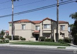 Corona apartment for rent - A house with a red tile roof and a palm tree in front.