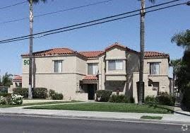 Corona apartment for rent - A house with a red tile roof and a palm tree in front.