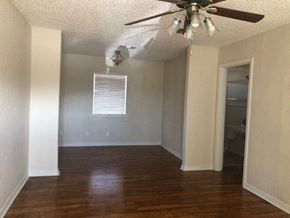 Snyder house for rent - A room with a ceiling fan and wooden floors.