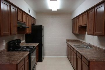 Goodyear apartment for rent - an empty kitchen with wooden cabinets and a black refrigerator