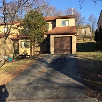 Highland house for rent - A house with a brown garage door and a tree in front.