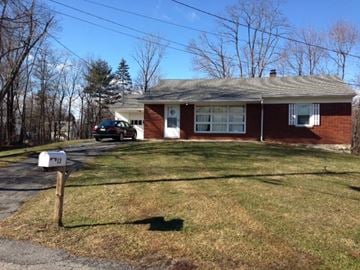 Poughkeepsie house for rent - A house with a red brick exterior and a grey roof with a mailbox in front.