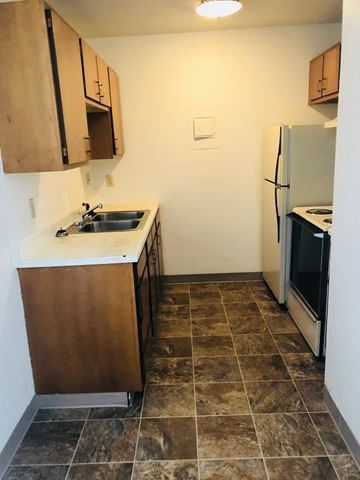 Moorhead apartment for rent - A kitchen with brown cabinets and a tiled floor.