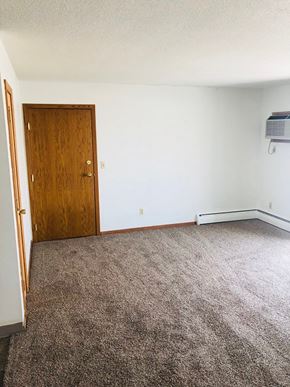 Moorhead apartment for rent - A room with a carpeted floor and a wooden door.