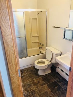 Moorhead apartment for rent - A white toilet is in a bathroom with a walk-in shower.