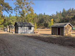 Placerville apartment for rent - Two small buildings sit in a field with trees in the background.
