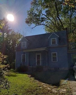 Bloomington house for rent - a blue house with the sun shining behind it
