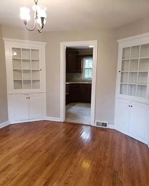 Bloomington house for rent - an empty living room with white cabinets and a wood floor