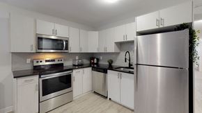 Ottawa apartment for rent - A modern kitchen with stainless steel appliances and white cabinets.