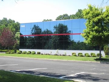 Mt. Laurel apartment for rent - A large building with a glass facade and a red stripe on it.