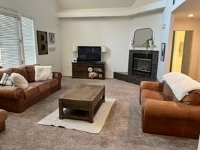 Arroyo Grande apartment for rent - A living room with a brown leather couch, a wooden coffee table, and a fireplace.