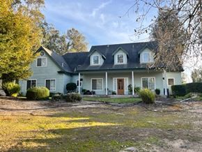 Arroyo Grande apartment for rent - A house with a blue siding and a brown door is surrounded by trees and grass.