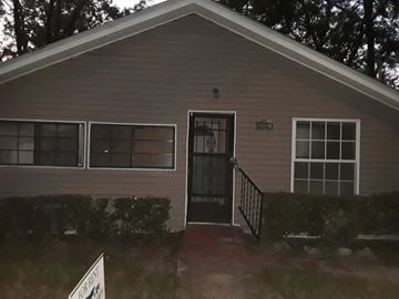 Tallahassee house for rent - A house with a grey siding and a black door.