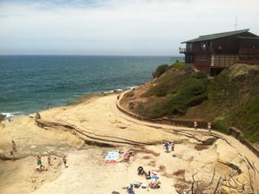 San Diego apartment for rent - A beach scene with people and a house by the sea.