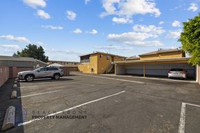 Downey apartment for rent - a parking lot with two cars in front of a building