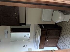 Stillwater house for rent - A white toilet is in a small bathroom with a wooden cabinet.