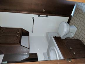 Stillwater house for rent - A white toilet is installed under a wooden cabinet.