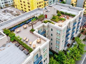 Seattle apartment for rent - A rooftop patio with tables and chairs overlooks a cityscape.