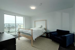 Vancouver apartment for rent - a bedroom with a bed and a black couch