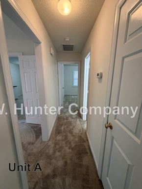 Wilson apartment for rent - A hallway with a carpeted floor and white walls.