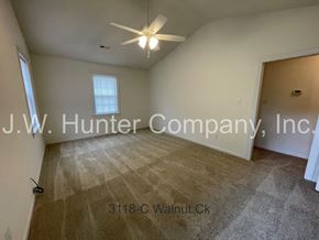 Wilson apartment for rent - A room with a carpeted floor and a ceiling fan, with the text "J.W. Hunter Company, Inc." and an address "3118-C Walnut Ck" overlaid on the image.