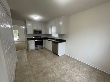 Wilson apartment for rent - A kitchen with white cabinets and a black countertop.