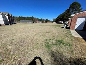 Wilson apartment for rent - A shadow of a person holding a camera is cast on a grassy field.